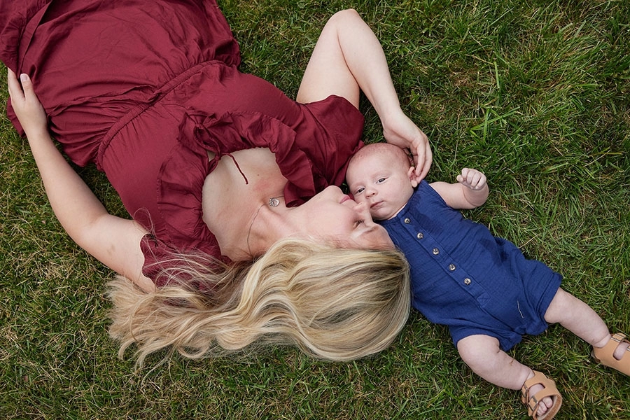 Mother and baby laying in a grass field.